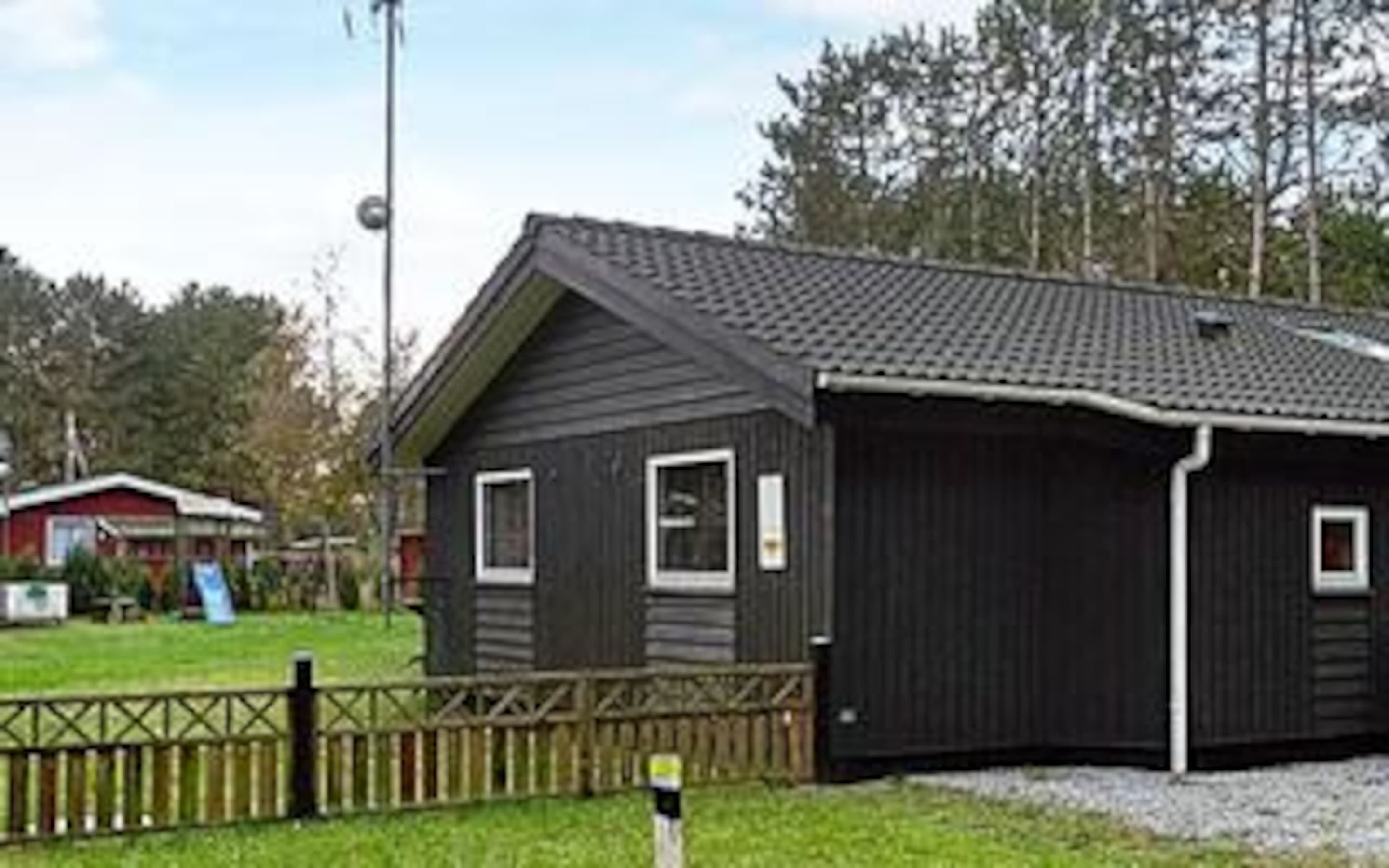 Ein eingeschossiges Gebäude mit dunkler Fassade, geneigtem Dach und einer kleinen Veranda.