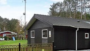 A single-story building with a dark exterior, a sloped roof, and a small porch area.