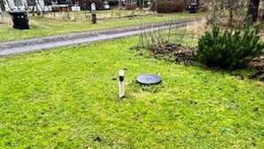 A grassy area with a metal object and a circular object on the ground.