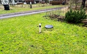 A grassy area with a metal object and a circular object on the ground.