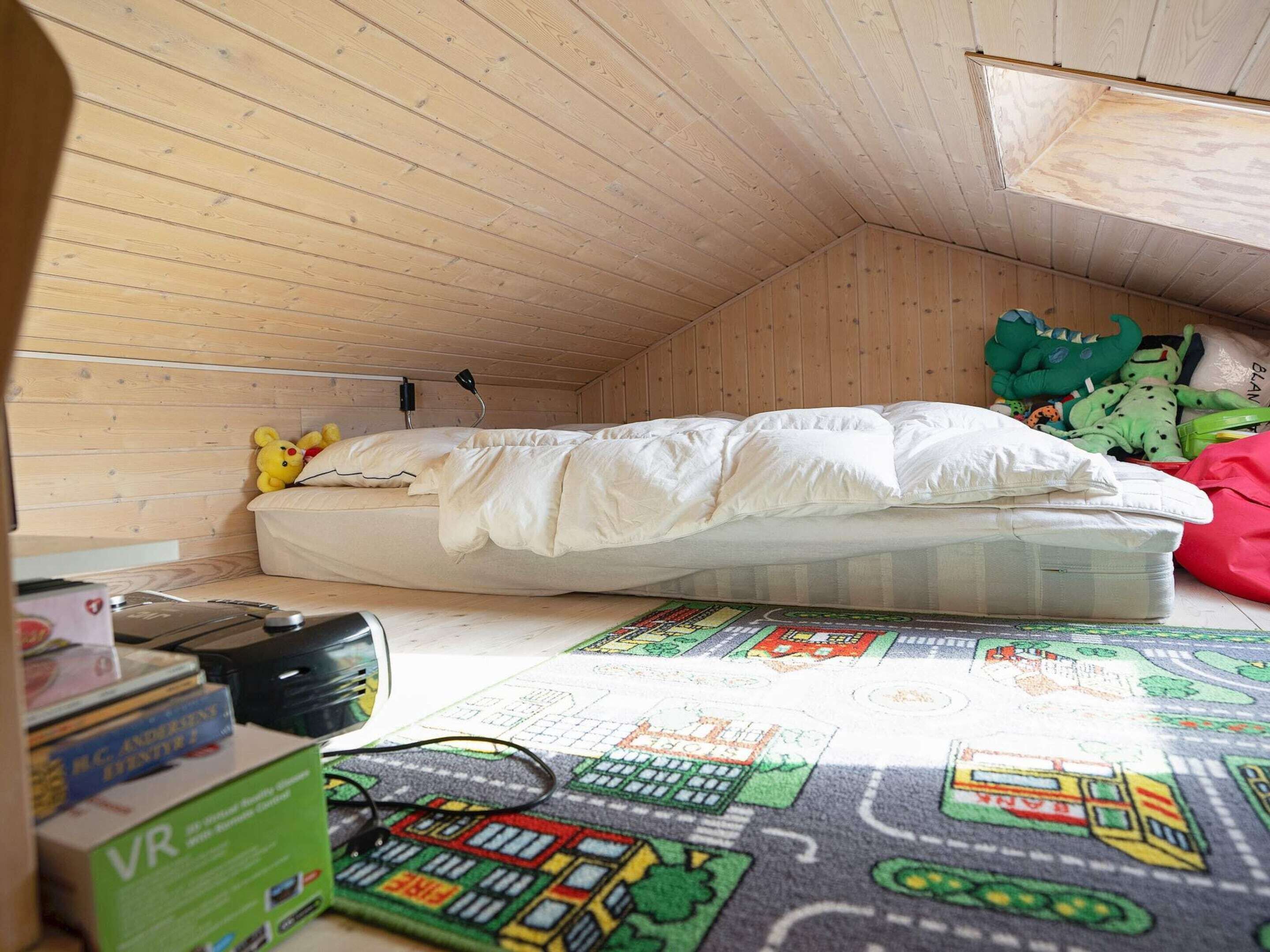 Ein kleiner Raum mit Holzwänden, einem Bett, einem Schreibtisch mit Computer und einem Fenster.