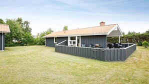 A single-story house with a fenced backyard, a patio with outdoor furniture, and a clear sky. - 5 Star Holiday Home in Hadsund (Hadsund)