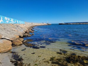 A coastal scene with clear water, rocks, and a pier.