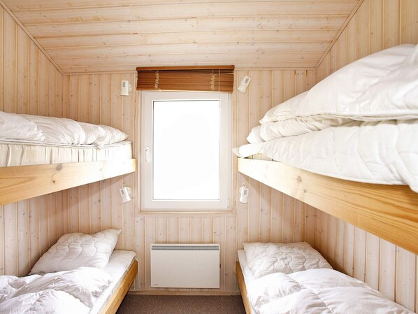 A room with two bunk beds, a window, and a wall-mounted heater.