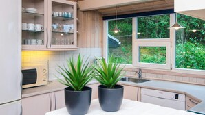 A modern kitchen with wooden cabinets, a microwave, a Bosch dishwasher, and two potted plants on the counter. - Secluded Holiday Home in Henne near Beach (Henne)