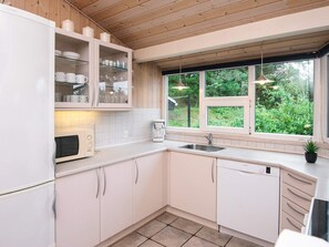 A modern kitchen with white cabinets, a built-in oven, a coffee maker, and a window with a view of greenery. - Secluded Holiday Home in Henne near Beach (Henne)