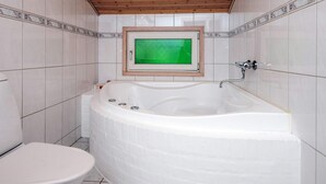 Ein Badezimmer mit einer weißen Badewanne, einer Toilette und einer Holzbalkendecke.
