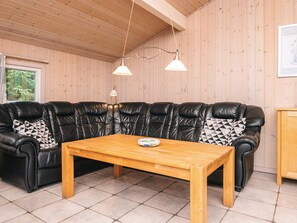 A cozy room with a black leather sofa, a wooden table, and two pendant lights. - Secluded Holiday Home in Henne near Beach (Henne)