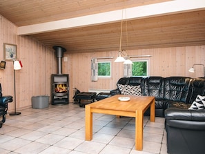 A cozy living room with a fireplace, leather sofa, and a wooden table. - Secluded Holiday Home in Henne near Beach (Henne)
