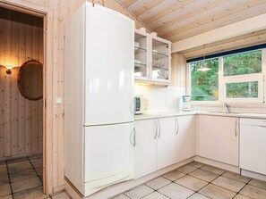 Una cocina moderna con armarios blancos, horno empotrado y ventana con vistas al exterior.