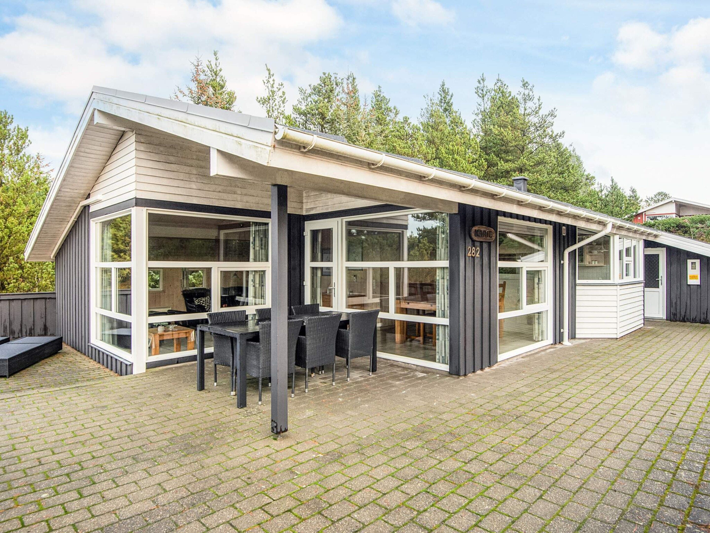 Ein modernes Haus mit überdachter Terrasse, großen Fenstern und einem Schild mit der Nummer 282.