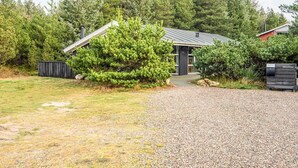 A small building with a gravel driveway, surrounded by dense trees and a wooden fence. - Secluded Holiday Home in Henne near Beach (Henne)