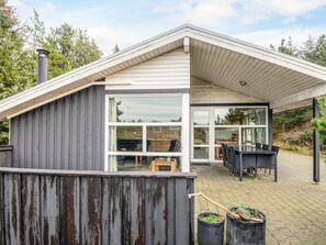 A modern house with a covered patio area, large windows, and outdoor furniture. - Secluded Holiday Home in Henne near Beach (Henne)