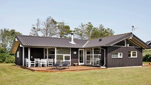 Uma casa moderna com varanda coberta, grandes janelas e chaminé.