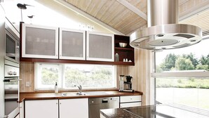 Uma cozinha moderna com lava-louças embutida, cafeteira e uma grande janela com vista para o exterior.