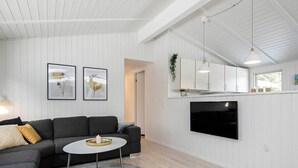 A modern living room with a grey sectional sofa, a round coffee table, and a flat-screen TV mounted on the wall. - Peaceful Holiday Home in Blavand Denmark With Terrace (Blavand)