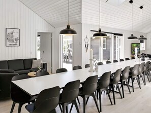 Un comedor moderno con una mesa larga, sillas negras e iluminación colgante.