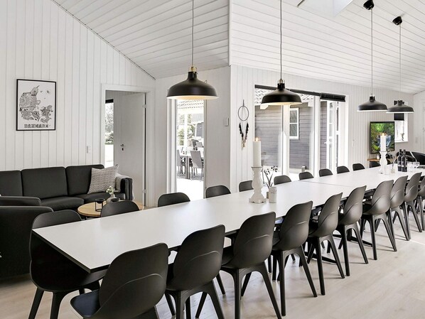 A modern dining area with a long table, black chairs, and pendant lighting.
