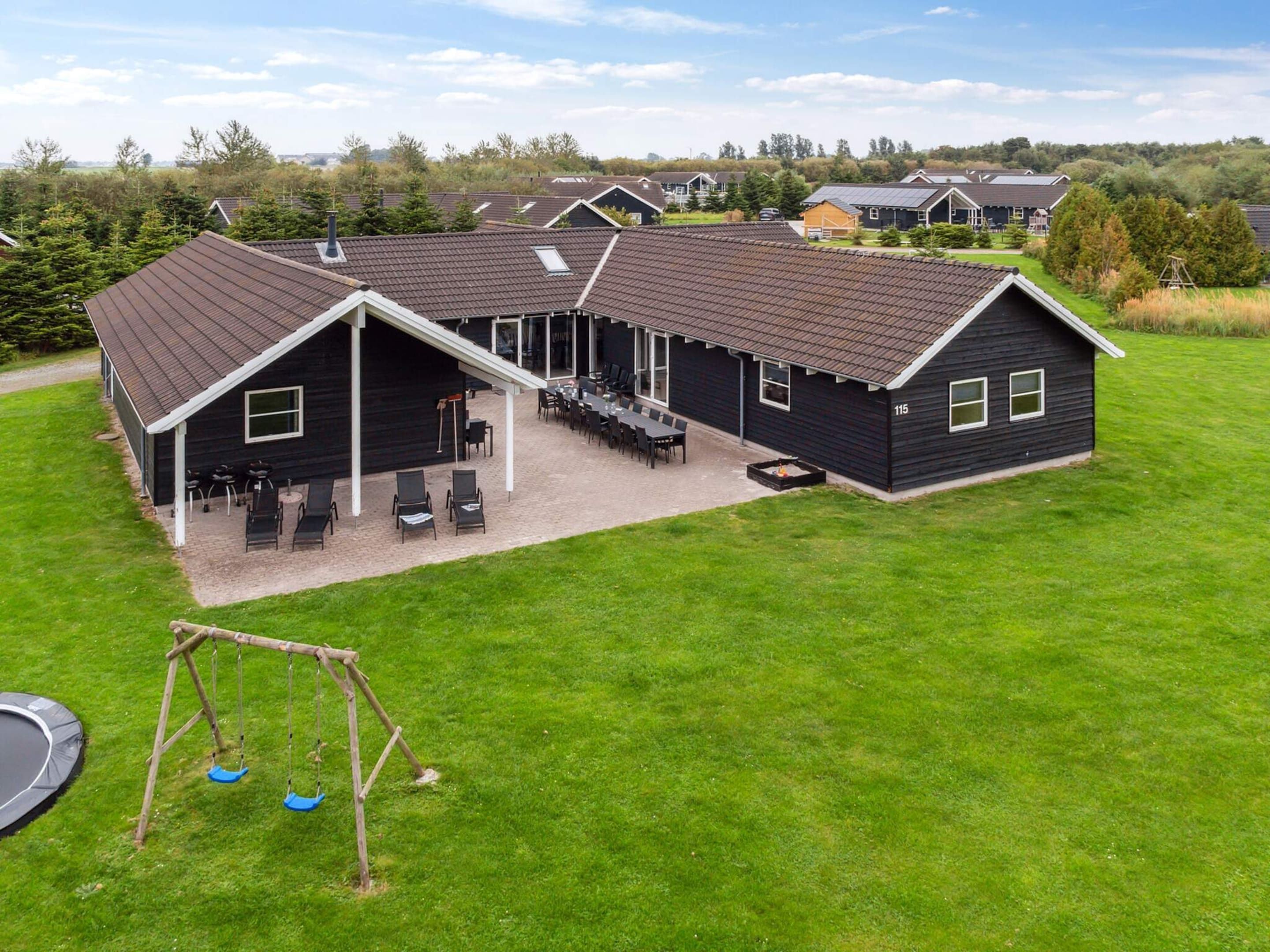 A residential building with a covered patio area, outdoor seating, and a swing set.