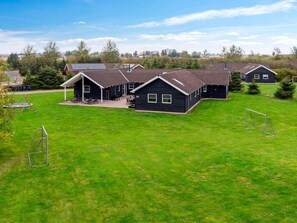 Et boligområde med flere huse, en velholdt græsplæne og en lille legeplads.