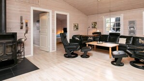 A cozy room with a wooden interior, a fireplace, leather furniture, and a dining table. - 5 Star Holiday Home in Hals (Hals)