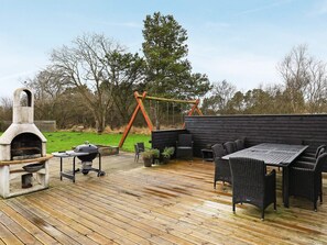 An outdoor patio with a grill, seating area, and a wooden deck. - 5 Star Holiday Home in Hals (Hals)