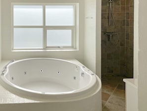 A bathroom with a freestanding bathtub, a shower area, and a window.