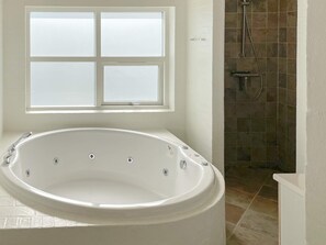 Une salle de bain avec une grande baignoire, une fenêtre et un espace douche.