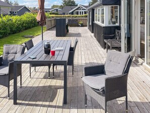 A wooden deck with a table and chairs, a patio umbrella, and a view of the surrounding houses.
