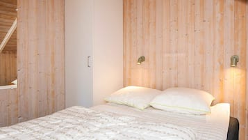 Un dormitorio con cama, armario y dos luces fijadas a la pared.
