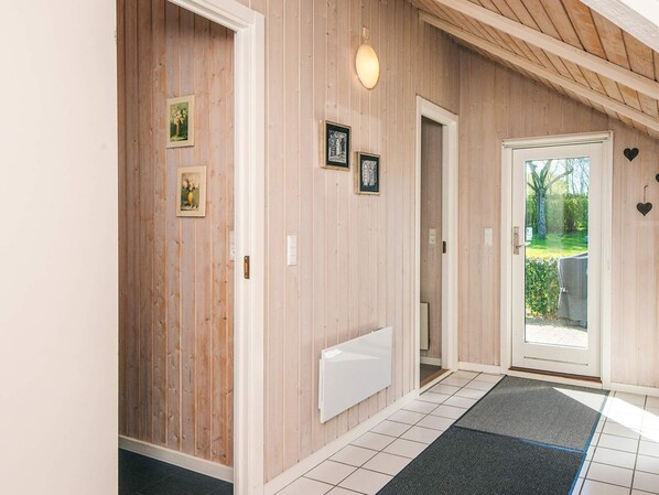 A hallway with wooden walls, a white radiator, and a door leading outside.