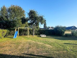 Un patio trasero con un columpio y un tobogán.