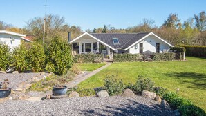 Une maison à deux étages avec un porche abrité, une cheminée bien visible et une pelouse bien entretenue.