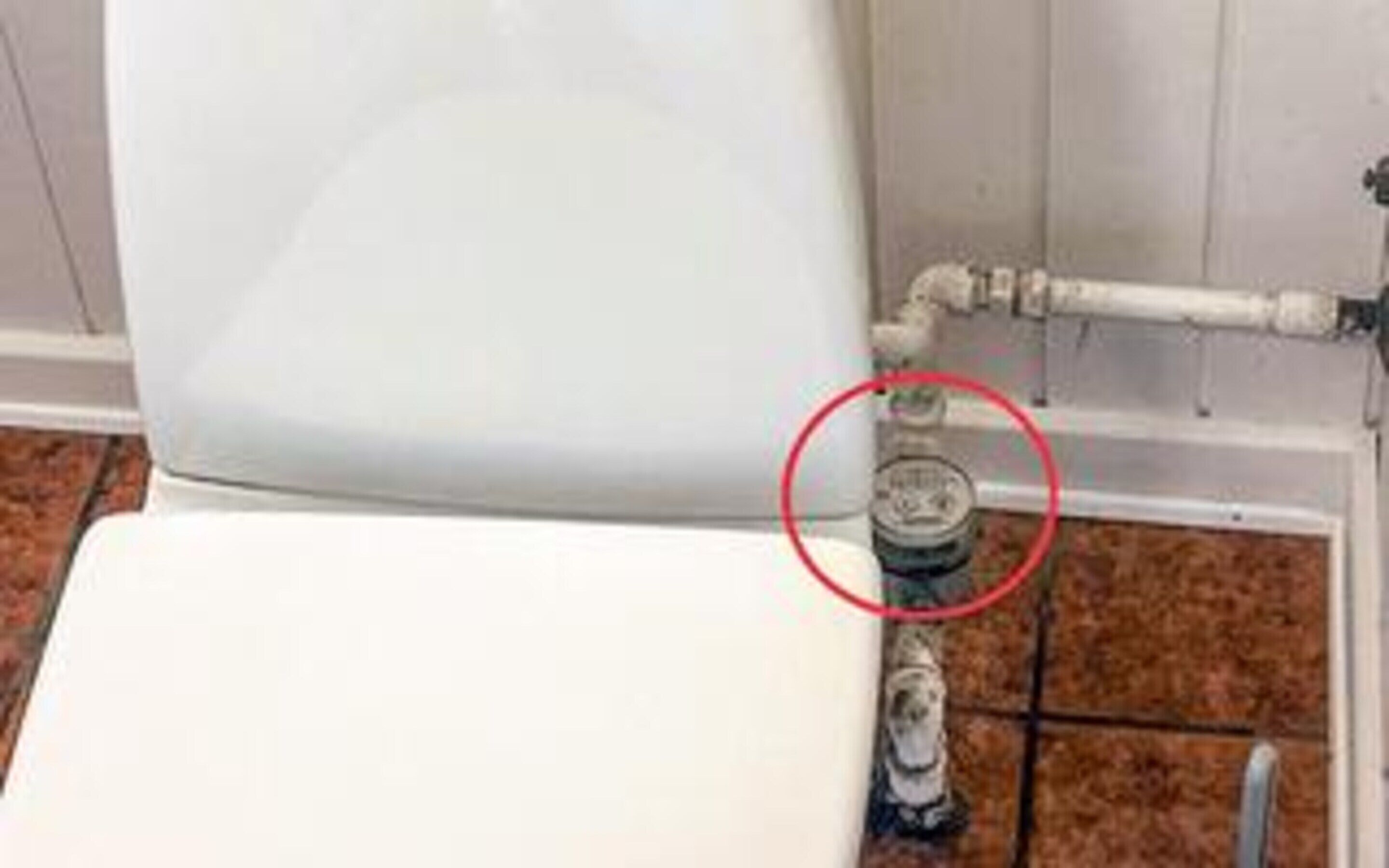 A toilet with a visible pipe connection.