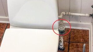 Des toilettes dont le raccord de tuyauterie est visible.