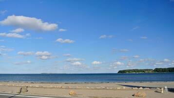 A coastal road with a clear sky, a view of the sea, and a distant island.