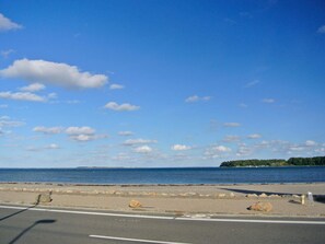 A coastal road with a clear sky, a view of the sea, and a distant island.