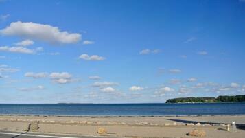 A coastal road with a clear sky, a view of the sea, and a distant island.