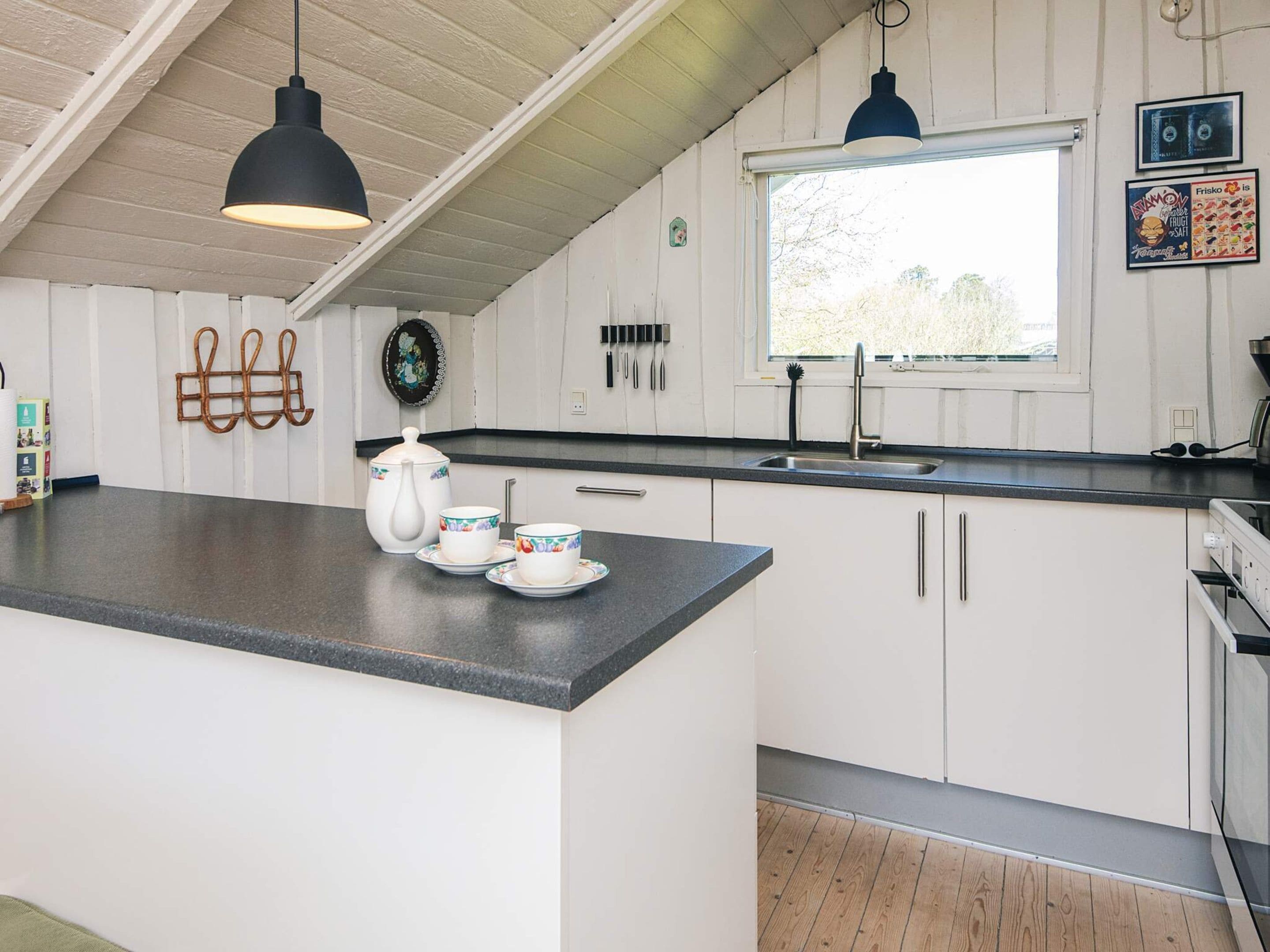 Una cocina con una isla central, un ventanal y un lavabo.