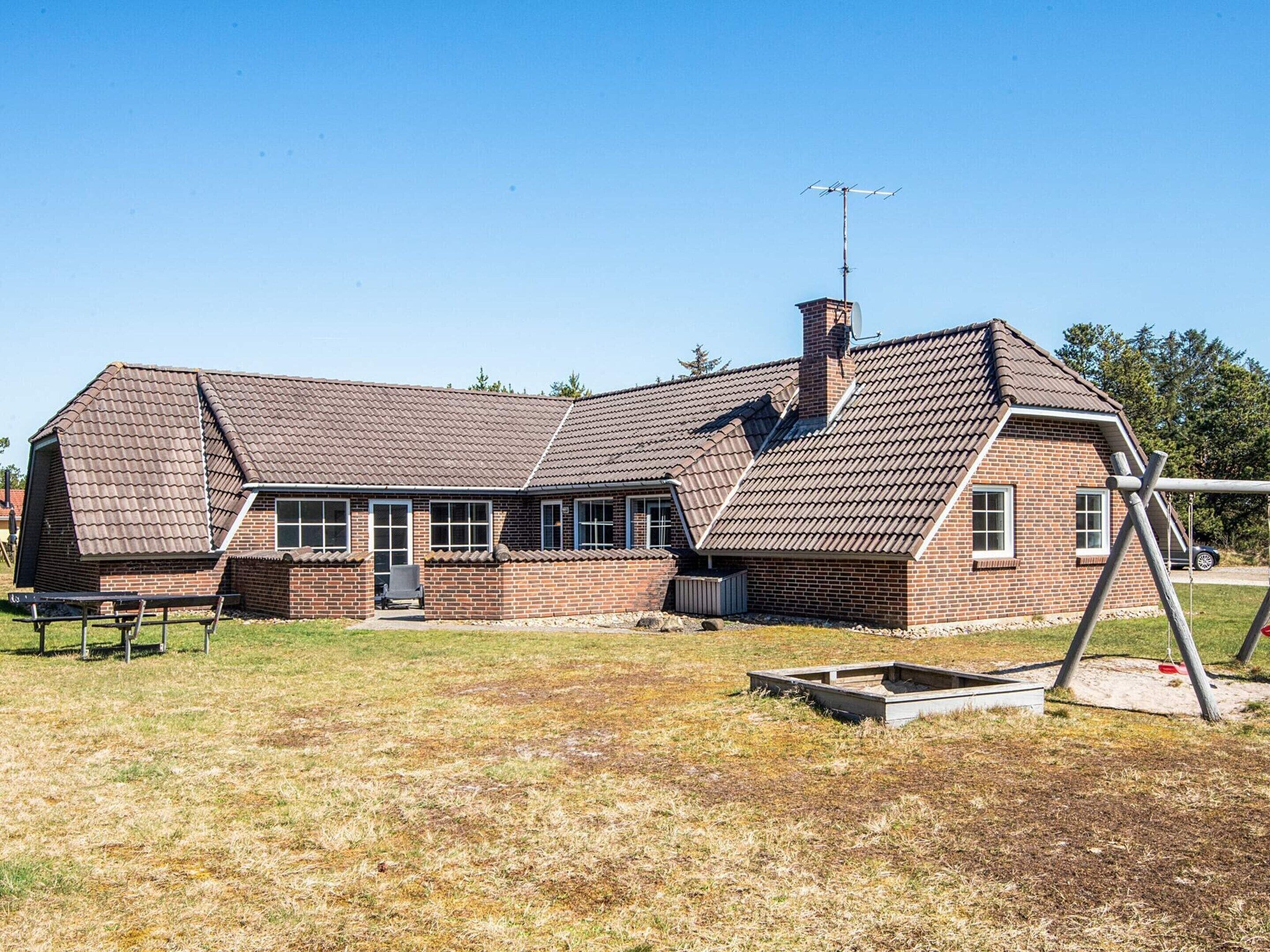 A two-story brick house with a sloped roof, a chimney, and a satellite dish.