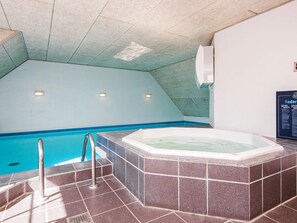 Piscina com hidromassagem, paredes azulejadas e teto com claraboia.