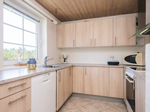 A modern kitchen with wooden cabinets, a built-in dishwasher, and a window providing natural light.