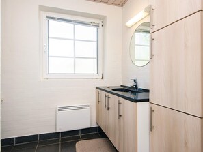 A small, clean bathroom with a window, a sink, a mirror, and a radiator.