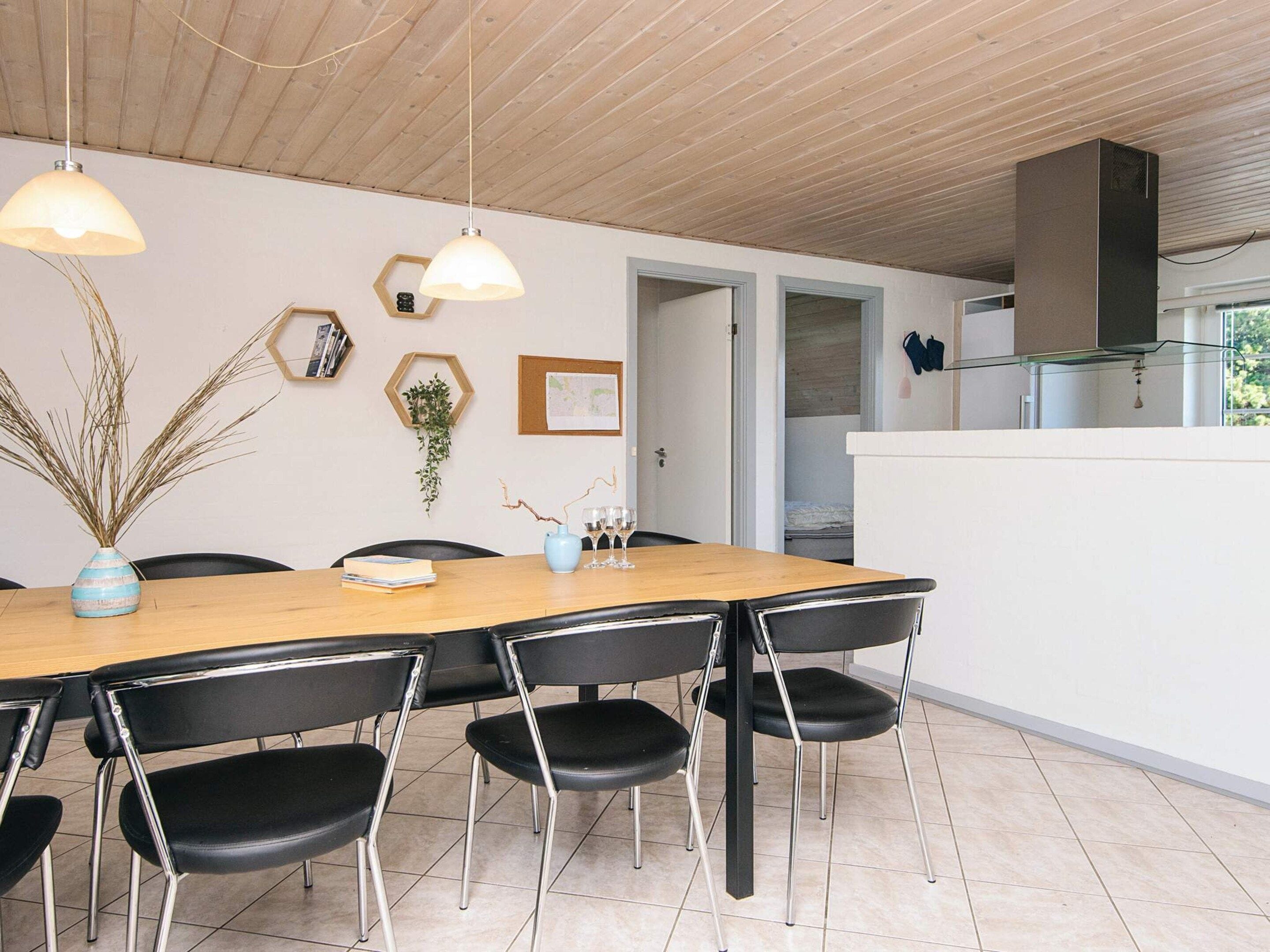A modern dining area with a wooden table, black chairs, and pendant lighting.