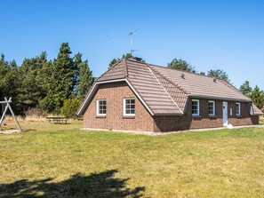 A single-story brick house with a sloped roof, a chimney, and a small porch.