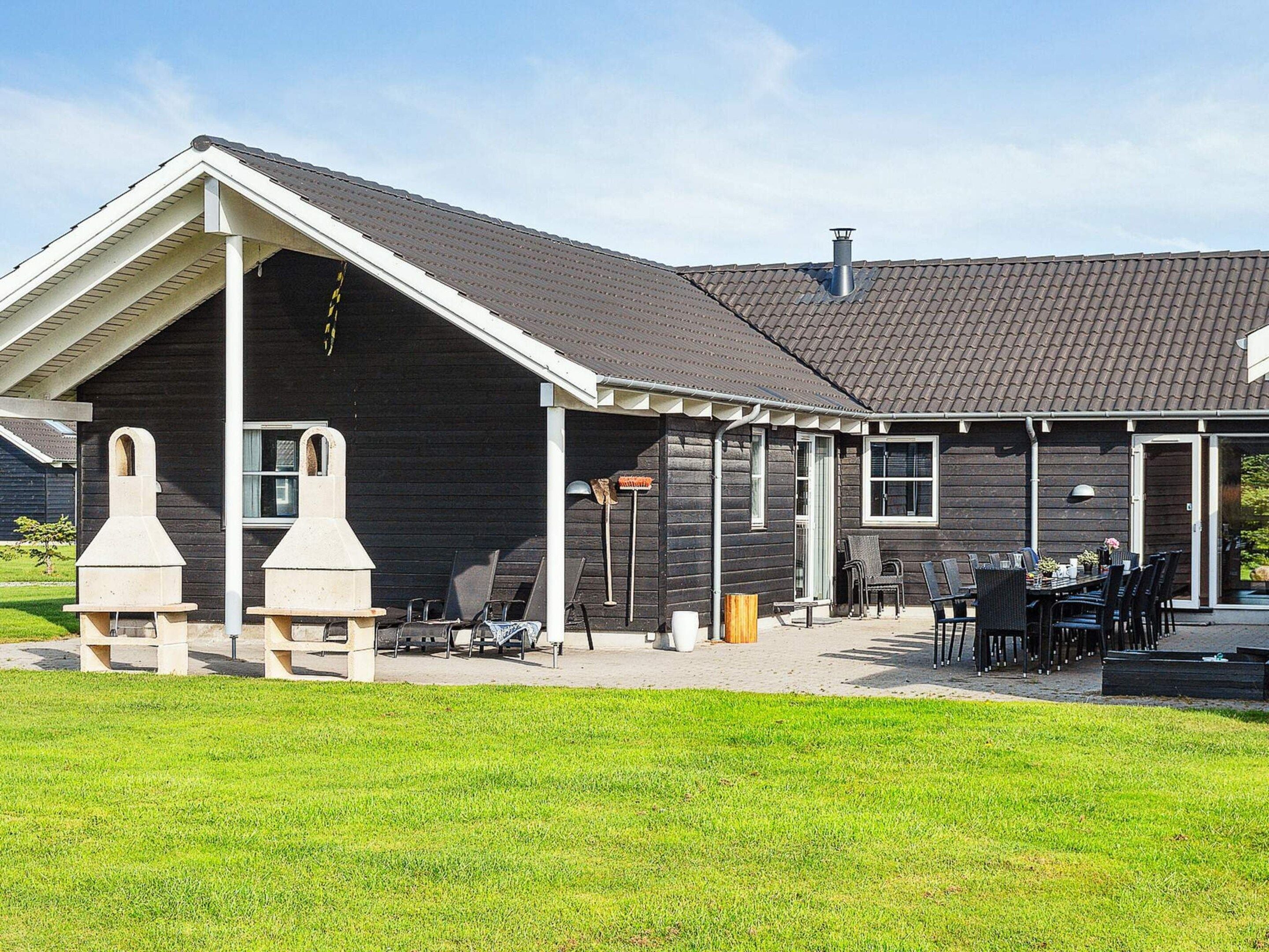 Een gebouw met een overdekt terras, buitenmeubels en een schoorsteen.