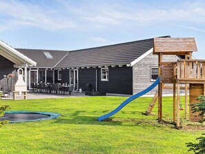 A residential backyard with a play area, a barbecue grill, and a dining area with outdoor furniture. - 5 Star Holiday Home in Idestrup (Idestrup)
