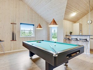 A pool table in a room with wooden walls and a sloped ceiling.