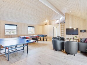 Een kamer met een tafeltennistafel, een tafelvoetbaltafel en een aan de muur bevestigde flatscreen-televisie.