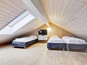 Quarto em estilo loft com duas camas, uma televisão e um claraboia.